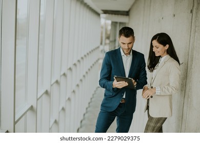 Handsome young modern business people using digital tablet in the office corridor - Powered by Shutterstock