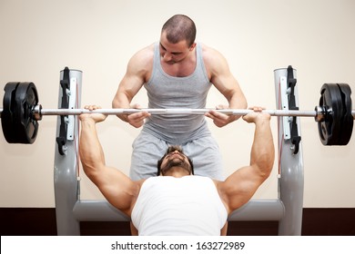 A Handsome Young Muscular Sports Man Doing Bench Press With A Little Help