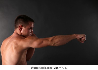 Handsome young muscular sportsman boxing on dark background - Shutterstock ID 215747767