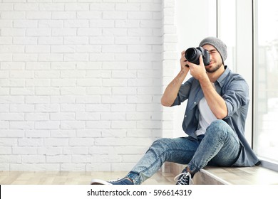 Handsome young photographer sitting on window sill