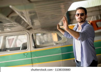 Handsome young pilot checking his ultralight airplane in the hangar before flight - Powered by Shutterstock
