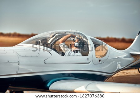 Handsome young pilot checking his ultralight airplane before flight.