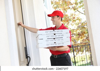 A handsome young pizza delivery man holding a pizza