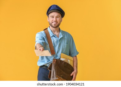 Handsome young postman on color background