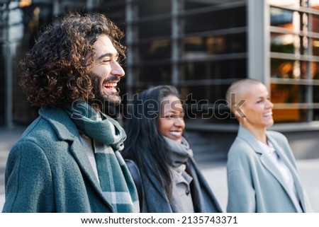 Handsome young professional man with long curly hair wearing a scarf outside the work place in winter