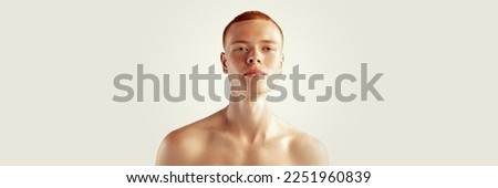 Handsome young red-haired man posing isolated over grey studio background. Male natural beauty. Concept of men's health, posing, beauty, body and skin care. Horizontal banner
