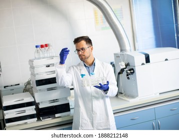 Handsome young researcher workin with chemical samples in laboratory with HPLC system and  chromatography equipment