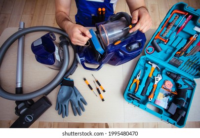 Handsome Young Serviceman Is Repairing Modern Vacuum Cleaner In His Office