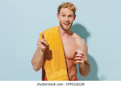 Handsome Young Sexy Man In Red Shorts Swimsuit Yellow Towel Relax Near Hotel Pool Hold Beer Bottle Drink Ale Point Finger Camera On You Isolated On Blue Background Summer Vacation Sea Sun Tan Concept