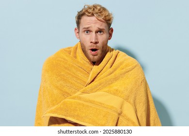 Handsome Young Shocked Man 20s Wearing Red Shorts Swimsuit Warepped In Yellow Towel Relax Near Hotel Pool In Cold Cloudy Weather Isolated On Pastel Blue Background Summer Vacation Sea Sun Tan Concept