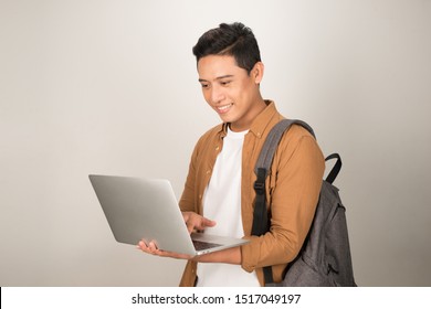 A Handsome Young Student Using Laptop And Carrying Backpack Isolated On White Background