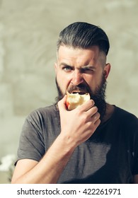 Handsome Young Stylish Hipster Man With Long Beard In Grey Shirt Eating Apple Outdoor With Brunette Hair