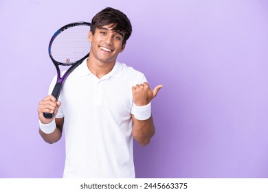 Handsome young tennis player man isolated on ocher background pointing to the side to present a product - Powered by Shutterstock