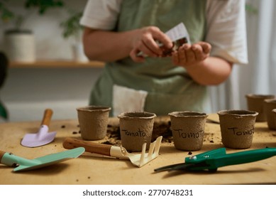 Hand-Sowing Seeds using Garden Tools. Gardener hand-sows seeds into peat pots.