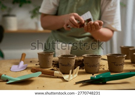 Hand-Sowing Seeds using Garden Tools. Gardener hand-sows seeds into peat pots.