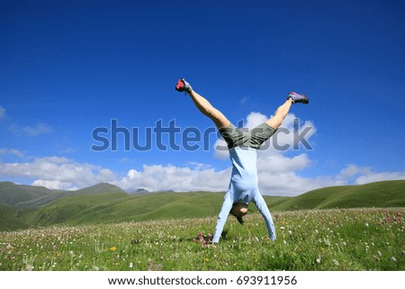 handstand woman have fun in a mountain peak meadow
