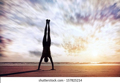 Handstand yoga pose by man silhouette on the beach near the ocean in India