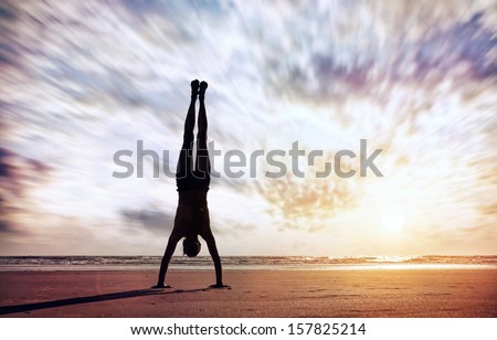 Handstand yoga pose by man silhouette on the beach near the ocean in India