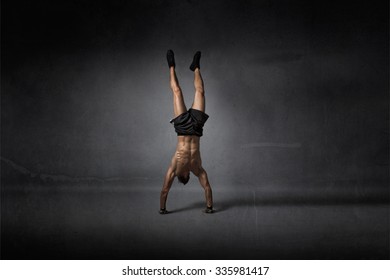 handstanding for athletic man, dark background