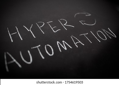 Handwriting Of HYPER AUTOMATION In White Colour By Chalk On Rough Blackboad.