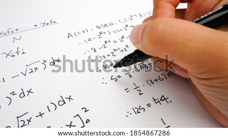 Handwriting to solve math formulas holding a computer pen. Math Formulas solves the test, practice, test or exam, background concept in math class.