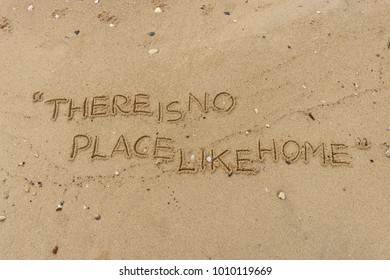 Handwriting  words "THERE IS NO PLACE LIKE HOME." on sand of beach.