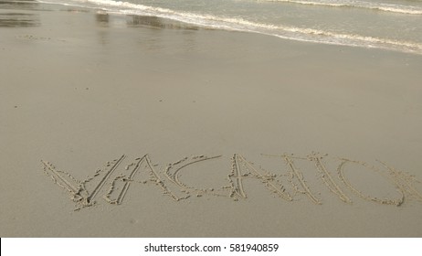 Handwriting words "VACATION" on sand of beach  