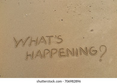 Handwriting  words "WHAT'S HAPPENING?" on sand of beach.