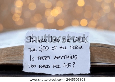 Handwritten Christian quote for God's supreme power, authority, and greatness over creation in front of open holy bible with bokeh background. Close-up. Jesus Christ's glory, love, and care concept.