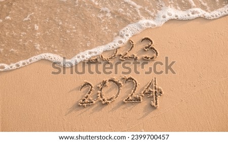 Handwritten inscription 2023 and 2024 on the beach in the sunset time. The concept of Goodbye 2023 and Happy New Year 2024