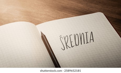 A handwritten inscription "Średnia" on a grille of an open notebook on a wooden countertop, next to a black pencil, lighting of light. (selective focus), translation: Average - Powered by Shutterstock - Get 15% off with code: PIKWIZARD15
