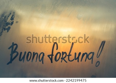 Handwritten Italian message Buona fortuna is Good luck on misted glass on sunset frost window Foto stock © 