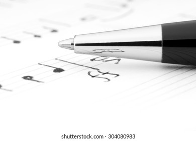 A handwritten notation on which lies a ballpoint pen.