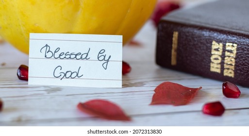 A handwritten note: Blessed by God Jesus Christ with Holy Bible Book. The Christian biblical concept of thanksgiving for God's blessings and gifts. Fall season background with pumpkin and red leaves.