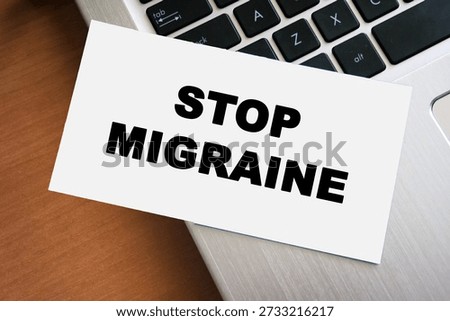 Handwritten note displaying the words STOP MIGRAINE on a white paper placed on a laptop keyboard. This image symbolizes health awareness and pain management strategies.