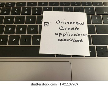 A handwritten note on a computer keyboard as a reminder to submit an application for the Universal Credit program in Great Britain - Shutterstock ID 1701137989