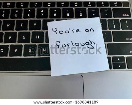 A handwritten note on a computer keyboard stating you’re on furlough. Furlough is a leave of absence or a temporary layoff from work