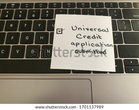 A handwritten note on a computer keyboard as a reminder to submit an application for the Universal Credit program in Great Britain