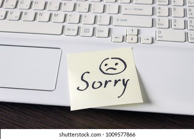 Handwritten note is on the keyboard. - Sorry. Sad smiley face drawn in black. - Shutterstock ID 1009577866