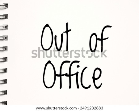 A handwritten note on a white sheet of paper in a spiral notebook with the words Out of office, suggesting a temporary absence or unavailability in a professional setting