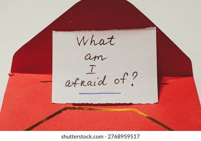 Handwritten note in a red envelope poses a question about fear and introspection
