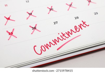 Handwritten word Commitment in red ink on a paper calendar with several dates crossed out to track personal goals.