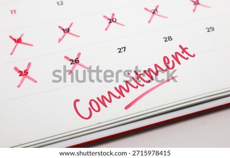 Handwritten word Commitment in red ink on a paper calendar with several dates crossed out to track personal goals.