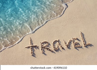 Handwritten Word Travel On Sand Of Beach With Soft Blue  Ocean Wave On Background