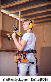 Handy Woman With Short Hair With Headphones Working With Drill.