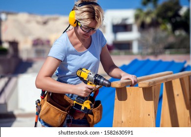 Handy Woman With Toolsbelt And Yellow Drill In Her Hands Outdoors