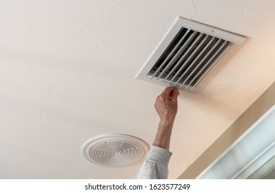 Handyman Adjusting HVAC Ceiling Air Vent. Air Flow Adjustment For Overhead Home Heat And Air Conditioning Ventilation Duct.