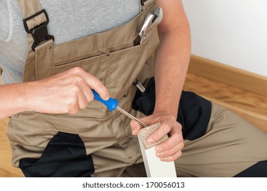 Handyman In Brown Uniform Repairing Broken Table Leg