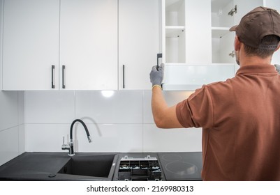 Handyman Checking The Doors On A Freshly Installed Wall Mounted Kitchen Storage Cabinet Combination Making Sure The Job Was Done Right.