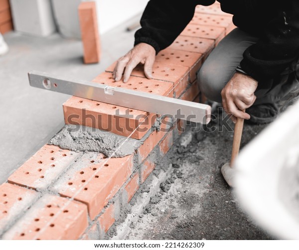 handyman checking the surface level of the brick\
wall with the spirit\
level